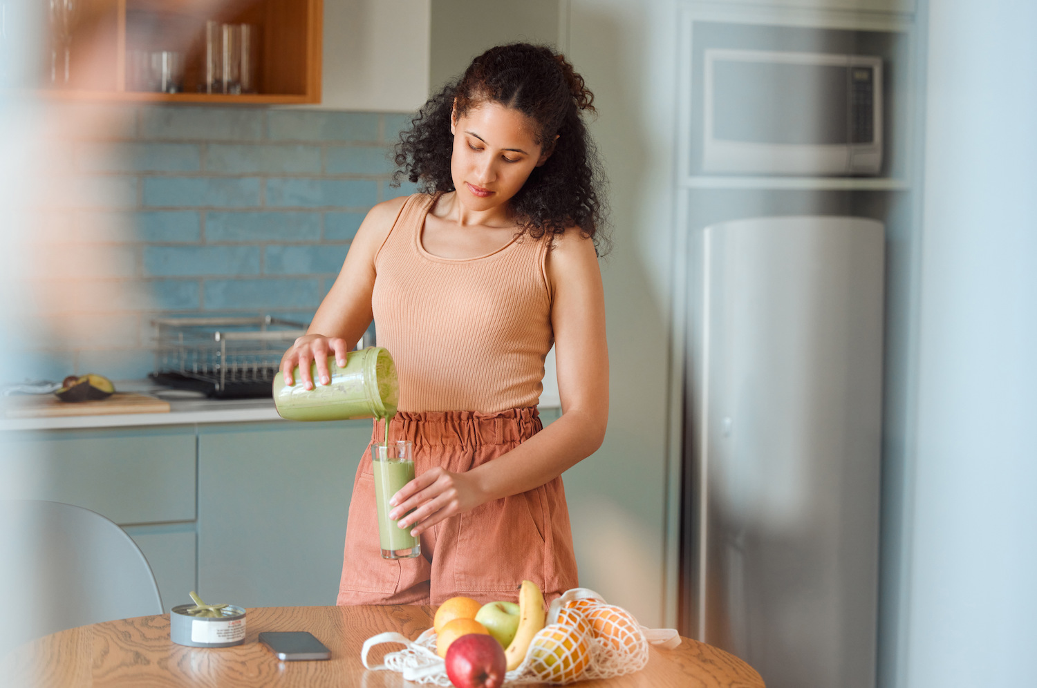Healthy, nutrition and wellness lifestyle young woman making fresh, green detox fruit smoothie